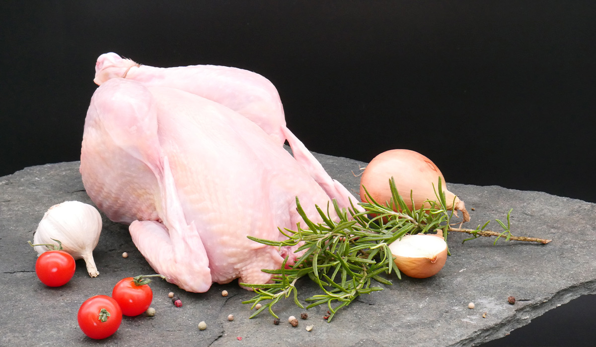 Frisches Bio-Hähnchen aus eigener Erzeugung mit Kräutern und Gemüse angerichtet.